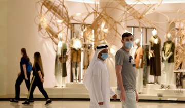 People wearing masks for protection against the coronavirus, walk in the Mall of Dubai. (AFP)