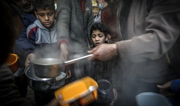 A boy waits as Palestinian Walid al-Hattab (R) distributes soup to people in need during the Muslim fasting month of Ramadan in Gaza City on April 14, 2021, amid the COVID-19 pandemic. (AFP/File Photo)