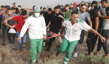 Medics evacuate a wounded person from the fence of Gaza Strip border during Saturday’s protest  to mark the burning 52 years ago of Al-Aqsa Mosque. (AP)