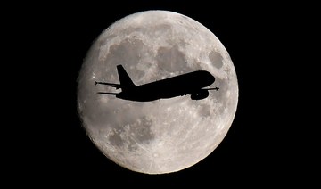 A passenger plane passes in front of the moon as it makes its final landing approach to Heathrow Airport in London. (Reuters/File Photo)