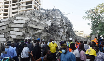 People stand to look at the rubble of a 21-storey building under construction that collapsed in the Ikoyi district of Lagos, on November 1, 2021. (AFP)