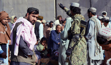 A Taliban fighter (R) gestures to people waiting to cross into Pakistan at the Afghanistan-Pakistan border crossing point in Spin Boldak on November 3, 2021, after authorities reopened the border following nearly a month-long closure. (AFP)