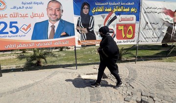 A woman in Baghdad strolls past campaign posters before the parliamentary election on October 10. (Reuters/File Photo)