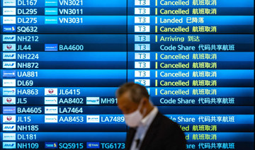  A man walks past an arrivals board showing cancelled flights at Tokyo's Haneda international airport on November 30, 2021. (AFP)