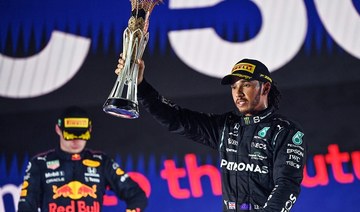 Winner Mercedes' British driver Lewis Hamilton (R) reacts with his trophy flanked by second-placed Red Bull's Dutch driver Max Verstappen (L) on the Jeddah podium. (AFP)