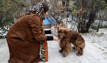 An Iranian woman plays with her dog in a yard near her house in northern Tehran, on December 5, 2021. (AFP)