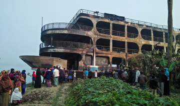 Villagers look at a burnt-out ferry after it caught on fire killing at least 39 people in Jhalkathi, 250 kilometers (160 miles) south of Dhaka, on Dec. 24, 2021. (AFP)