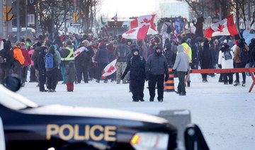 Police keep watch as demonstrators participating in a protest organized by truck drivers opposing vaccine mandates continue to gather on the streets in the day on February 19, 2022 in Ottawa. (AFP)