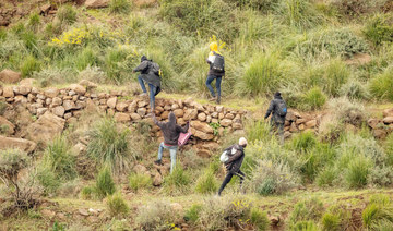 Migrants climb a ledge along a mountain path after an attempted assault on the border fence separating Morocco from Spain’s North African Melilla. (AFP)