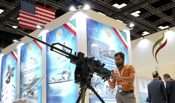 A visitor stands behind a machine gun in Iran's Pavilion at the DIMDEX exhibition in Doha, Qatar, on March 23, 2022. (AP Photo/Lujain Jo) 