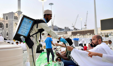 An employee at the Grand Mosque in Makkah hands out bottles of Zamzam water before iftar during Ramadan. (File/SPA)