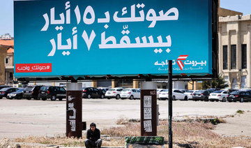 A youth sits underneath a giant billboard for the upcoming parliamentary election with text in Arabic reading "your vote on May 15 will nullify May 7" on display at the Martyrs' Square in the centre of Lebanon's capital Beirut on April 13, 2022. (AFP)