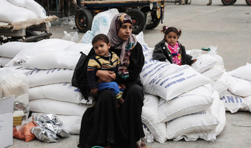 A Palestinian woman sits with a child after receiving food supplies from the United Nations' offices at the United Nations' offices in the Khan Yunis refugee camp in the southern Gaza Strip. (AFP file photo)