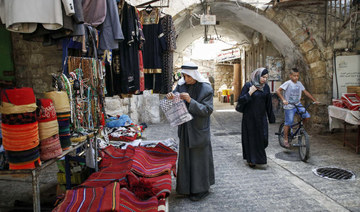A Palestinian man browses merchandise as another woman walks by in an alley in the old market of the divided West Bank city of Hebron. (AFP file photo)