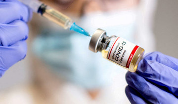 A woman holds a small bottle labelled with a "Coronavirus COVID-19 Vaccine" sticker and a medical syringe. (REUTERS file photo)