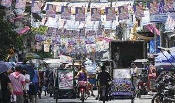 Residents pass by election campaign posters near a polling center in Manila, Philippines on Friday, May 6, 2022. (AP)