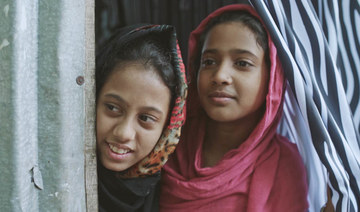 Two girls peek out from a zebra-print curtain hanged in their home in Karail, Dhaka’s largest slum area. (Supplied)