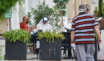 Men, one of whom is mask-clad, sit outside a cafe along Tahlia street in Riyadh. (AFP file photo)
