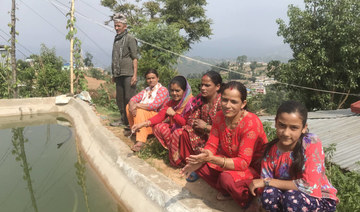 Residents of Kuinkel Thumka sit next to a conservation pond that supplies them with water during prolonged dry periods.