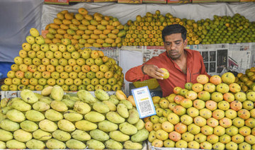 A vendor stacks mangoes at a stall at the Mango Mandi in Bangalore on May 6, 2022. (AFP)