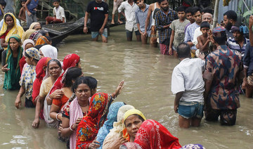 Flood affected people queue in knee-deep flood waters to collect food relief following heavy monsoon rainfalls in Sunamganj