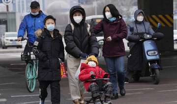 A child wearing a mask is pushed across a road in Beijing, Friday, Dec. 2, 2022. (AP)