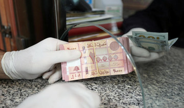 A customer wearing gloves holds Lebanese pounds at a currency exchange store in Beirut. (REUTERS)