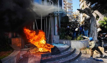 A protester throws a brick at a bank after setting fire to tyres during a demonstration in Beirut on February 16, 2023. (AFP)