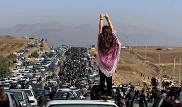 A woman stands on top of a vehicle as thousands make their way towards Aichi cemetery in Saqez, Kurdistan.