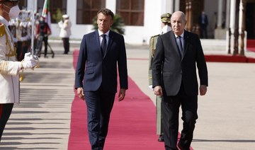 French President Emmanuel Macron walks with Algeria's President Abdelmadjid Tebboune at Algiers airport, in Algiers.