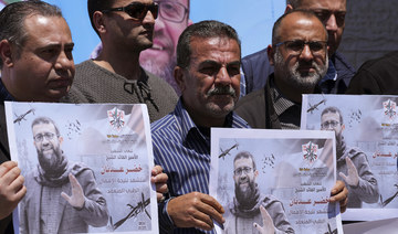 Palestinians hold pictures of Khader Adnan, a leader in the militant Islamic Jihad group, who died in Israeli prison.