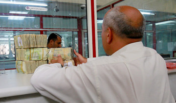 A man receives bands of Yemeni riyal banknotes at the Houthi-run Central Bank of Yemen in Sanaa, Yemen June 30, 2021. (REUTERS)