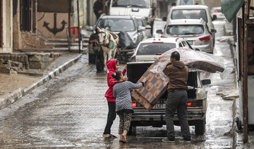 A man is assisted by children as he unloads mattresses from the back of a vehicle at Al-Shati camp for Palestinian refugees.