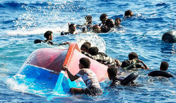 Migrants near their overturned boat during a rescue operation. (AP/File)