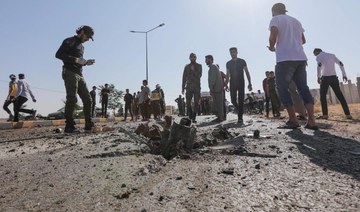 Passersby and gunmen gather at the site of a reported drone strike in Bzaah town near al-Bab in Syria's Aleppo governorate.