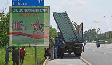 Workers install billboards along a roadside ahead of the visit of Chinese Vice Premier He Lifeng, in Islamabad on July 30, 2023.