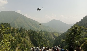 People watch as army soldier slings down from a helicopter during a mission to recover students stuck in a chairlift.