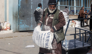 Palestinians carry bags of flour received as aid to poor families, at the UNRWA distribution center, in the Rafah refugee camp.