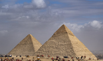 Camel guides wait near the Great Pyramid of Khufu and the Pyramid of Khafre at the Giza Pyramids necropolis.