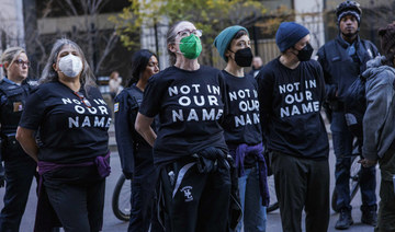 Arrested protesters chant as they await to board the transport outside the Accenture Tower in Chicago, Monday, Nov. 13, 2023. 