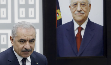 Palestinian PM Mohammad Shtayyeh stands next to a portrait of the Palestinian Authority’s President Mahmud Abbas.