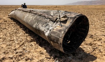 Photographers stand by the remains of a missile that landed on the shore of the Dead Sea.