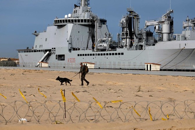 A French soldier and his dog patrols in front of the French LHD Dixmude military ship, which serves as a hospital to treat wounded Palestinians, as it docks at the Egyptian port of Al-Arish on January 21, 2024. (AFP)