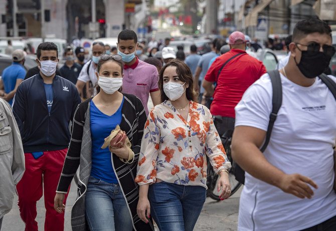 Moroccans wearing face masks walk along a street in the capital Rabat, after the authorities eased lockdown measures in some cities, that had been put in place in order to limit the spread of the novel coronavirus, on June 25, 2020. (AFP/File Photo)