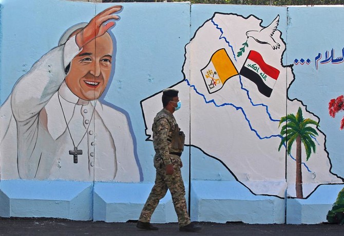 An Iraqi policeman walks past a mural depicting Pope Francis on the outer walls of Our Lady of Salvation (Sayidat al-Najat) Church, in Baghdad on February 22, 2021. (AFP)