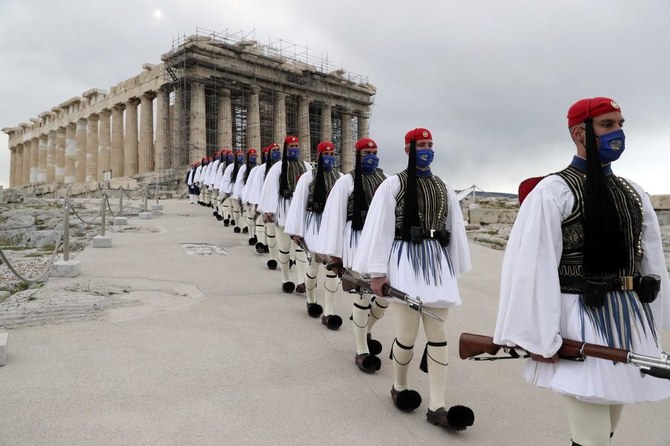 Members of the Presidential Guard walk in front of the Parthenon temple atop of Acropolis Hill after the Greek flag raising ceremony in Athens, on March 25, 2021. (AFP)