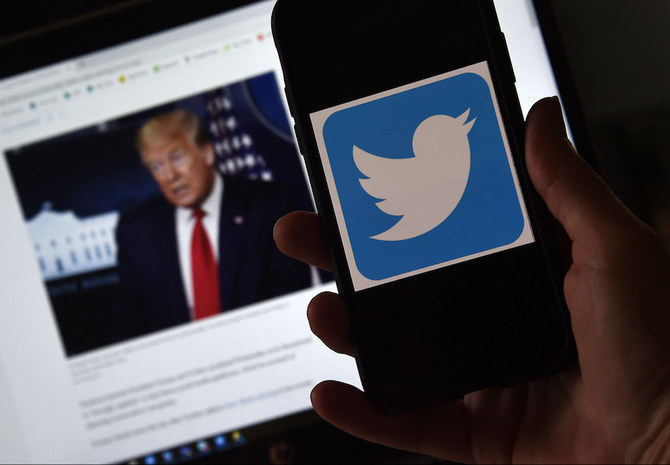 In this photo illustration, a Twitter logo is displayed on a mobile phone with a President Trump's picture shown in the background on May 27, 2020, in Arlington, Virginia. (AFP/File Photo)