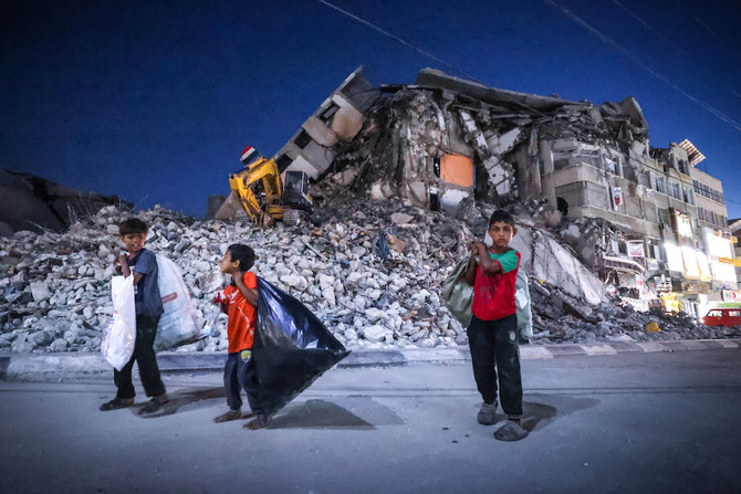 Palestinian boys walk past the destroyed Al-Shuruq tower in Gaza City's Al-Rimal neighbourhood which was targeted by Israeli strikes. (AFP)