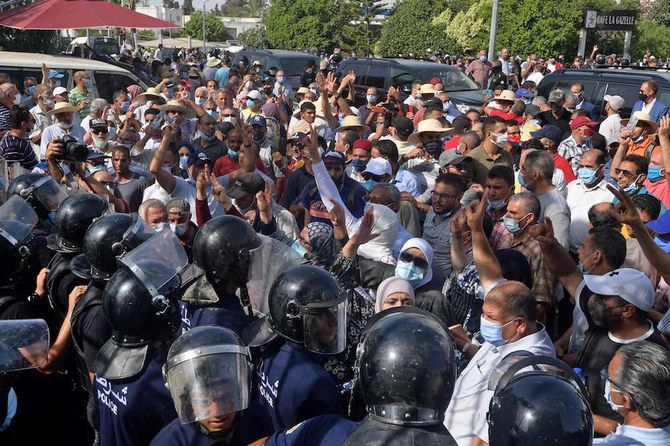 Tunisian security officers hold back protesters outside the parliament building in the capital Tunis on July 26, 2021, following a move by the president to suspend the country's parliament and dismiss the Prime Minister. (AFP)