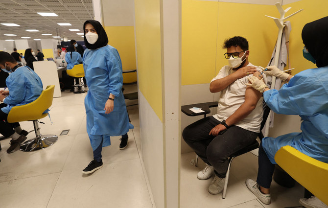 An Iranian health worker inoculates a man at a COVOD-19 vaccination center set up inside the Iran Mall in Tehran on August 14, 2021.(Photo by ATTA KENARE / AFP)